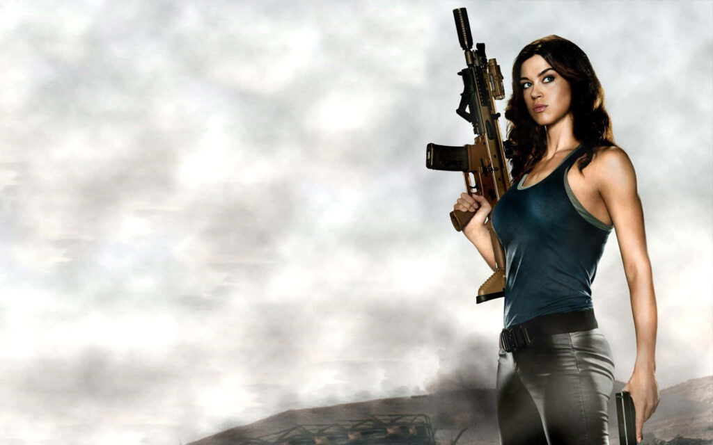 Adrianne Palicki holding rifle confidently against cloudy sky showing strength and determination Wallpaper