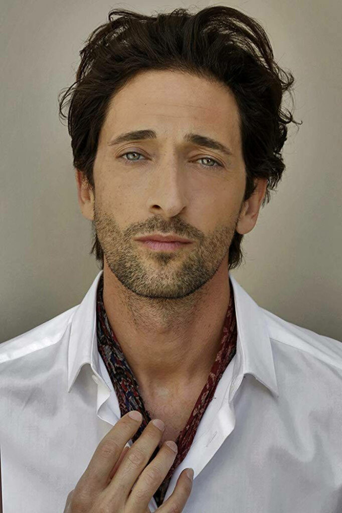 Close-up portrait of Adrien Brody with expressive eyes tousled hair white shirt and patterned scarf Wallpaper