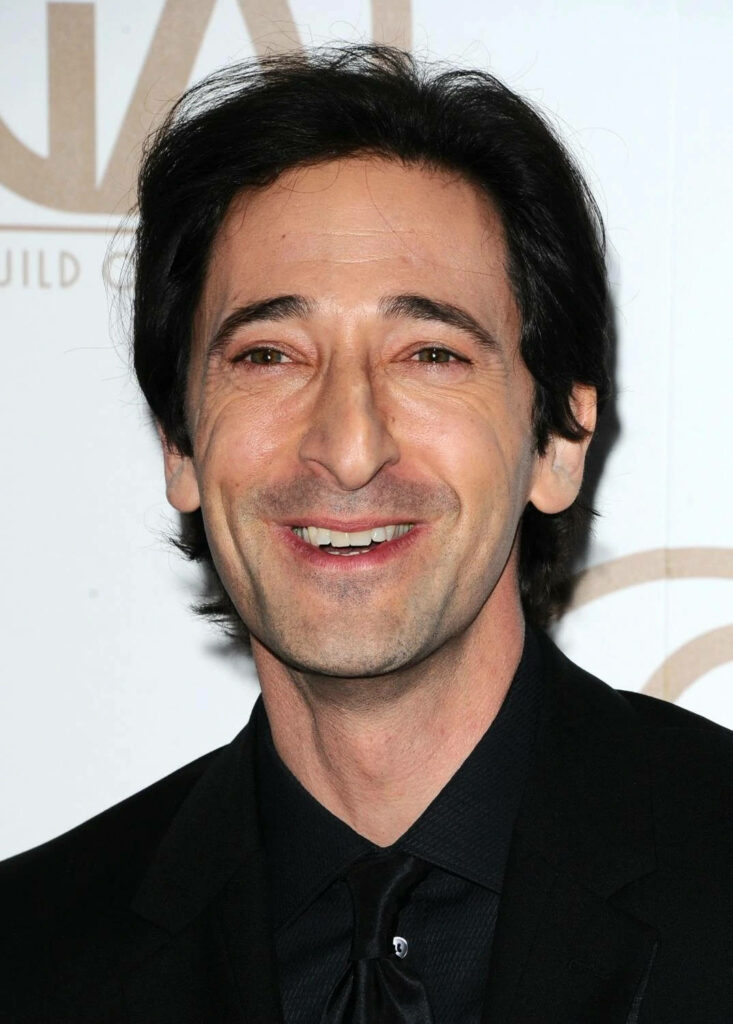 Adrien Brody smiling in black suit portrait on light background charismatic wallpaper