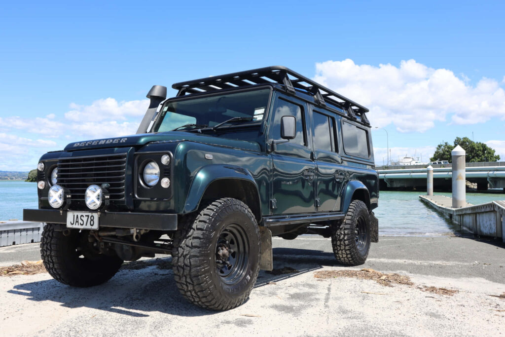 Adventure-Ready Land Rover Defender 4x4 Wallpaper Near Serene Waterfront