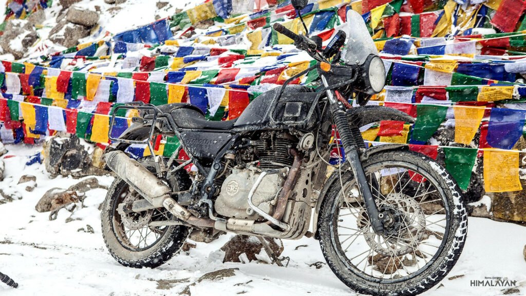 Rugged Himalayan Bike Wallpaper: Snowy Adventure & Tibetan Flags