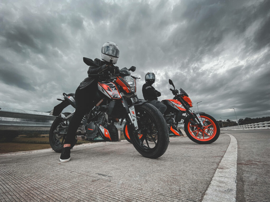 Adventure Awaits: KTM Duke 200 Riders Under Dramatic Cloudy Sky Wallpaper