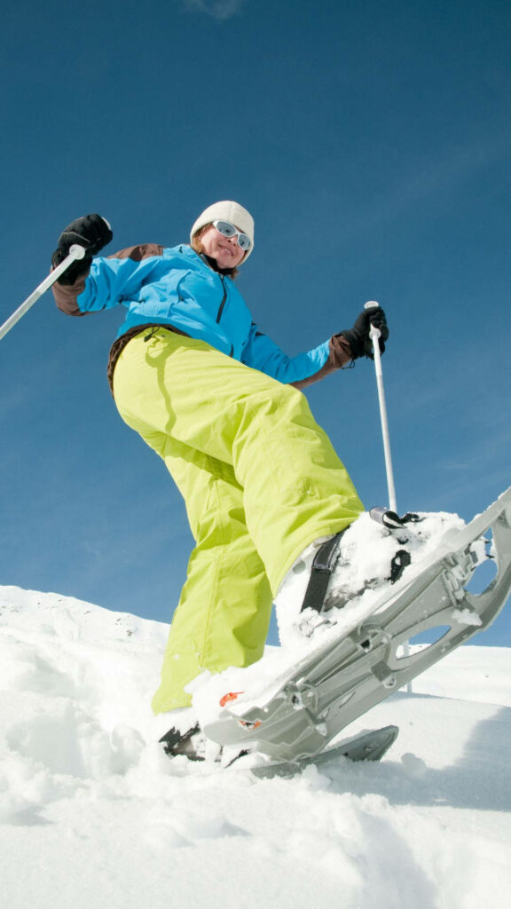 Confident Woman Snowshoeing on a Snowy Slope - Winter Adventure Wallpaper