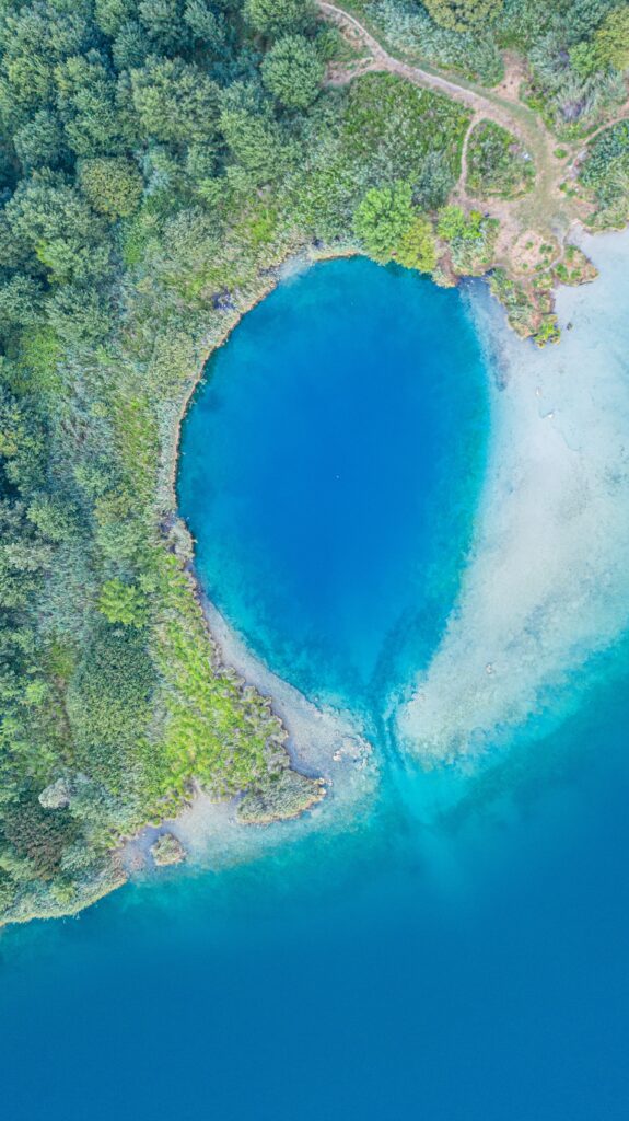 Aerial view of lush green coastline with turquoise and deep blue ocean waters wallpaper background