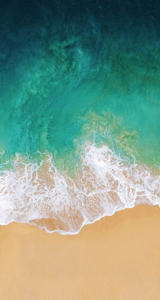 Aerial view of aqua blue ocean waves gently crashing on golden sandy beach calm coastal wallpaper