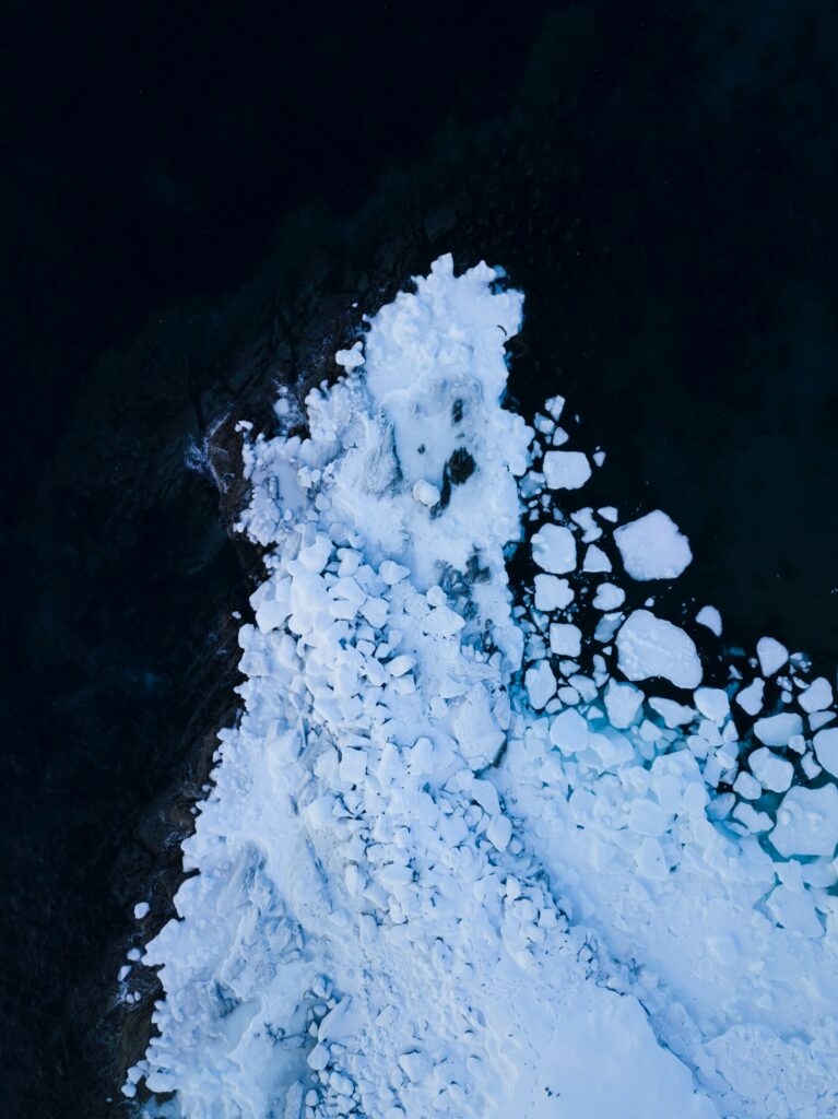 Aerial view of glacier ice shards contrasting with deep blue ocean natural landscape wallpaper