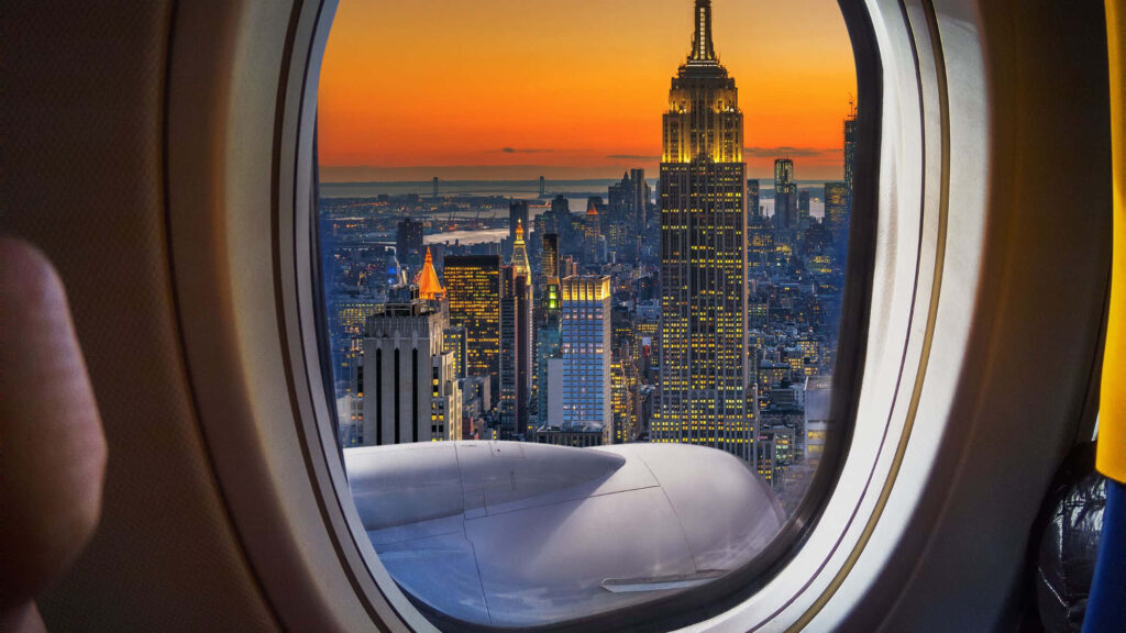 Skyscrapers and City Vibes: Marveling at the Empire State Building through an Airplane Window Wallpaper