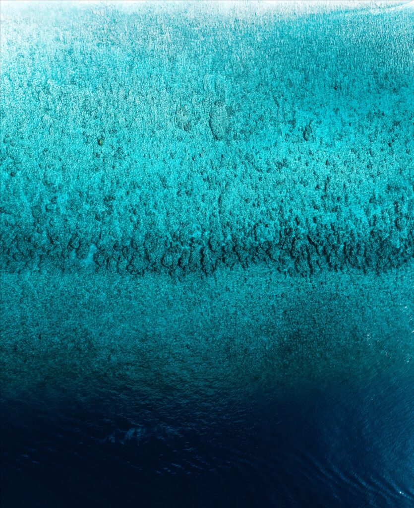 Aerial ocean view wallpaper with blue gradient rippling water from turquoise to deep navy tones