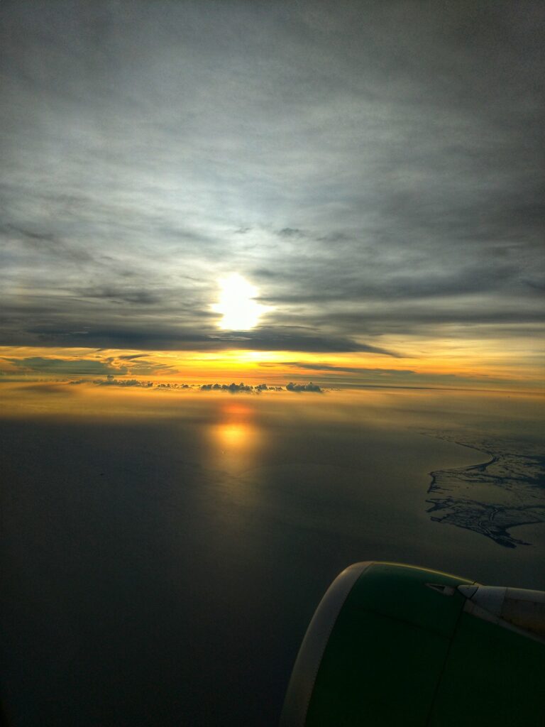 Aerial sunset view over calm sea with dramatic clouds and golden light reflecting on water Wallpaper