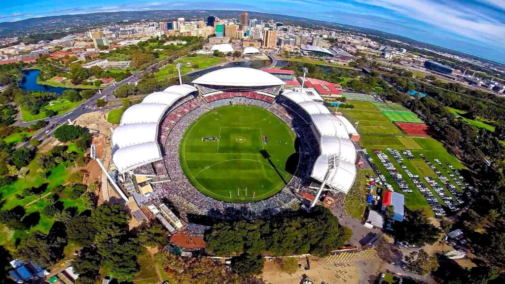 Aerial view of Adelaide Oval stadium with lush greenery and Adelaide city skyline background Wallpaper