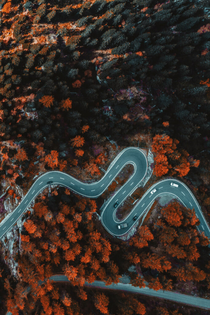 Aerial view of winding road through vibrant autumn trees in Austria HD wallpaper background