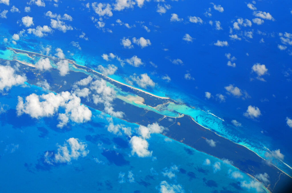 Aerial view of vibrant blue sea with scattered islands and white clouds creating serene landscape Wallpaper