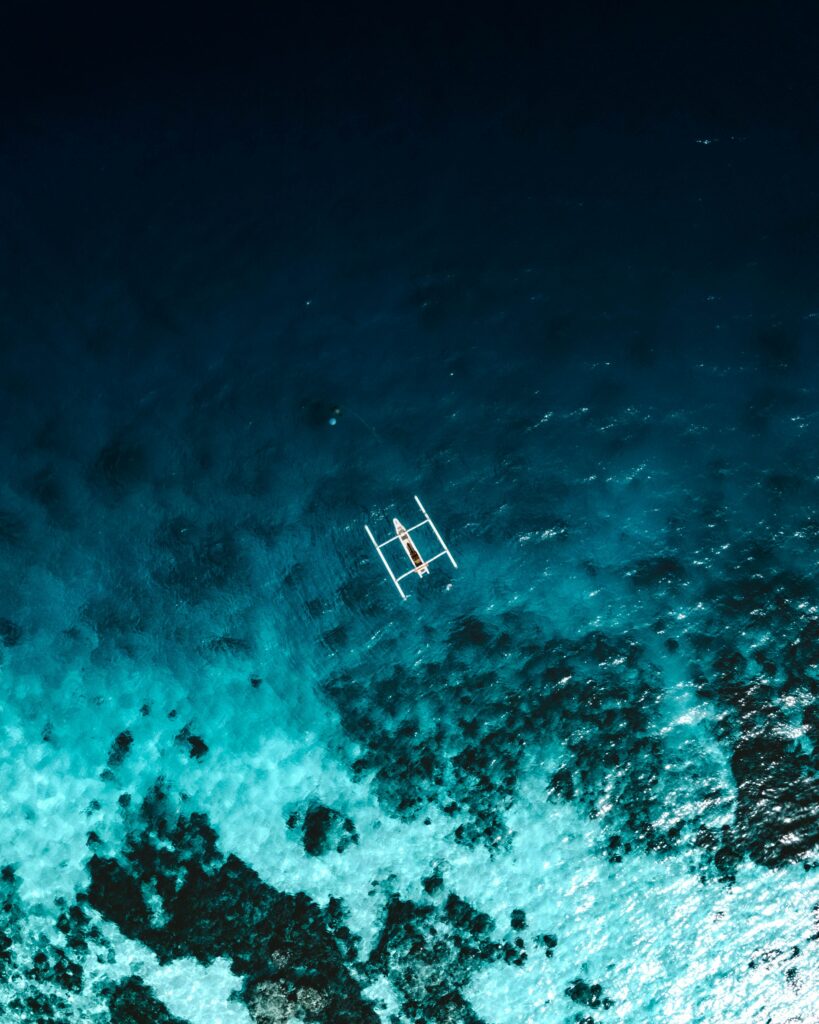 Aerial view of boat over vibrant reef with deep blue and turquoise waters ocean wallpaper background