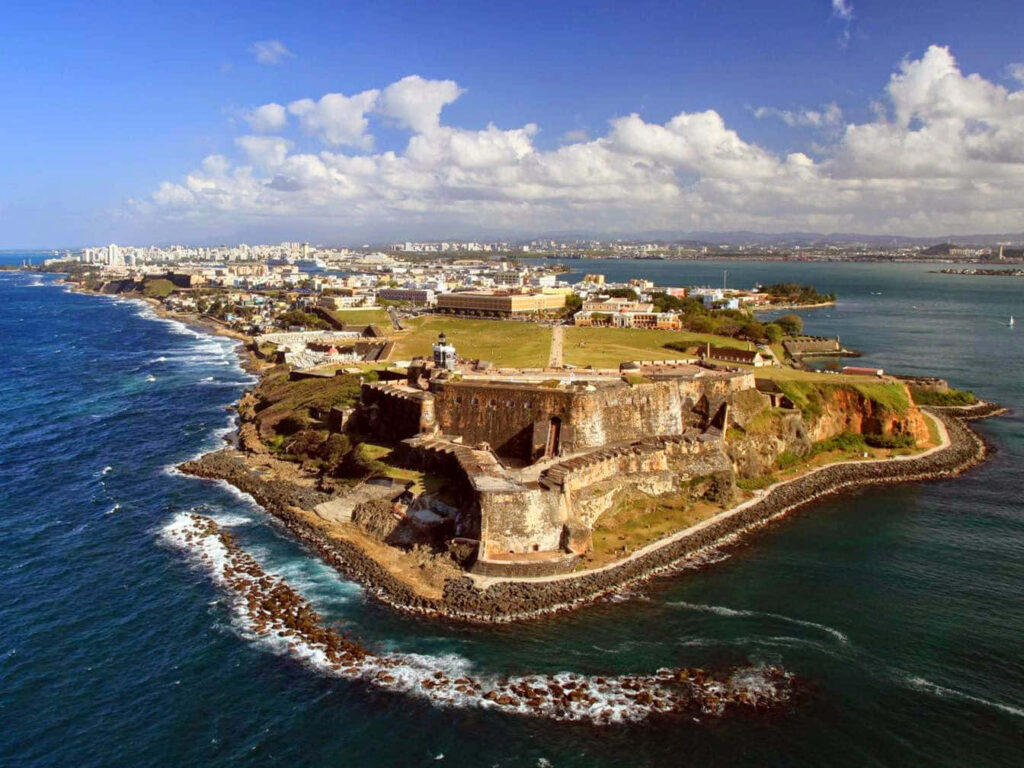 Aerial view of Castillo San Felipe del Morro fortress with ocean and San Juan cityscape background Wallpaper