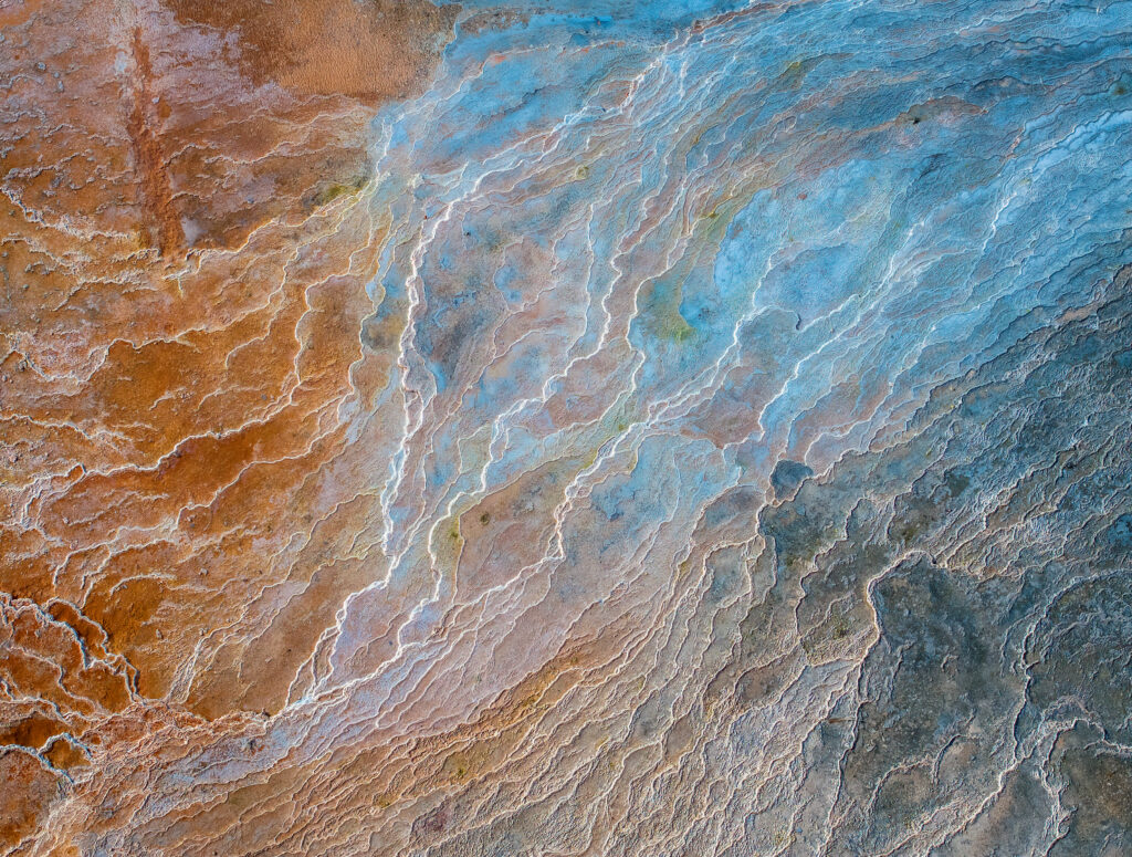 Aerial view of Earth with rust orange and blue tones showing rivers and geological textures wallpaper