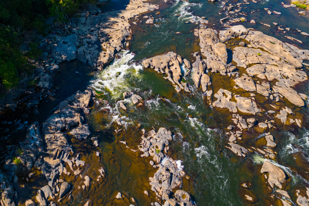 Aerial view of a clear river winding through rocky terrain surrounded by lush green nature wallpaper