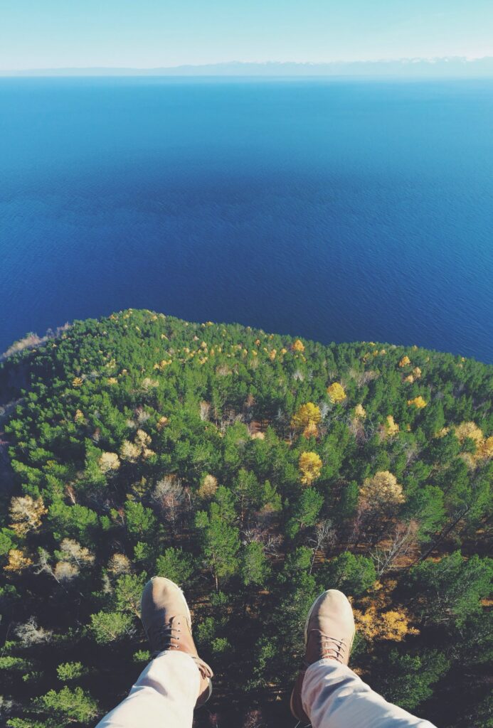 Aerial view of dense green forest and calm blue lake with boots floating above nature wallpaper