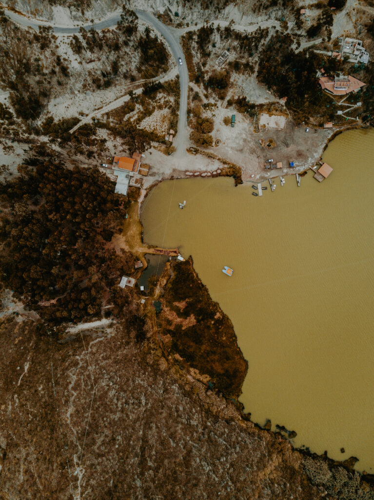 Aerial view of rugged bay coastline with brown earth tones yellow water boats and buildings wallpaper