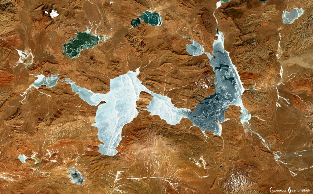 Aerial view of rugged brown mountains and winding blue rivers natural landscape wallpaper background