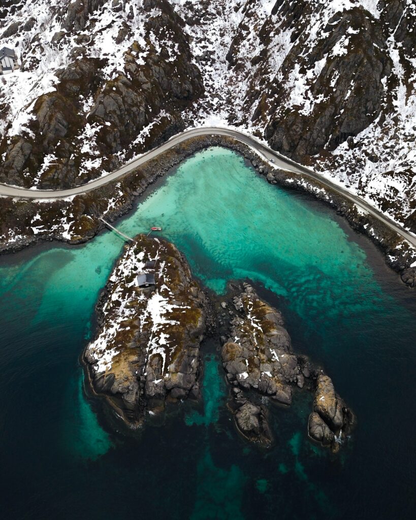 Aerial view of snowy mountain peaks and turquoise lake with winding road winter landscape wallpaper