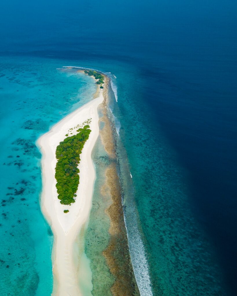Aerial view of tropical island with turquoise waters lush greenery coral reef and white sand beach Wallpaper