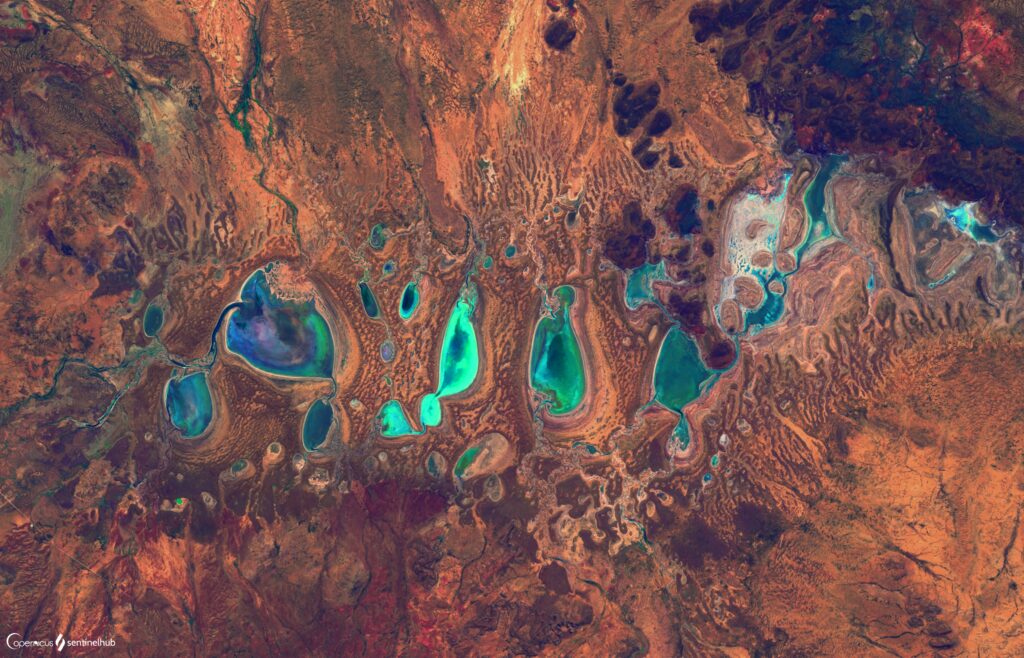 Aerial view of turquoise lakes and textured orange brown terrain natural landscape wallpaper background
