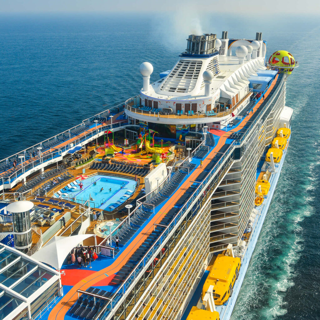 Aerial view of vibrant luxury cruise ship with pool slides sun decks sailing deep blue sea background Wallpaper