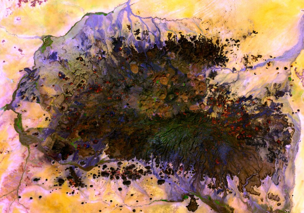 Aerial view of volcanic field with dark lava and vibrant yellow purple rugged terrain wallpaper background