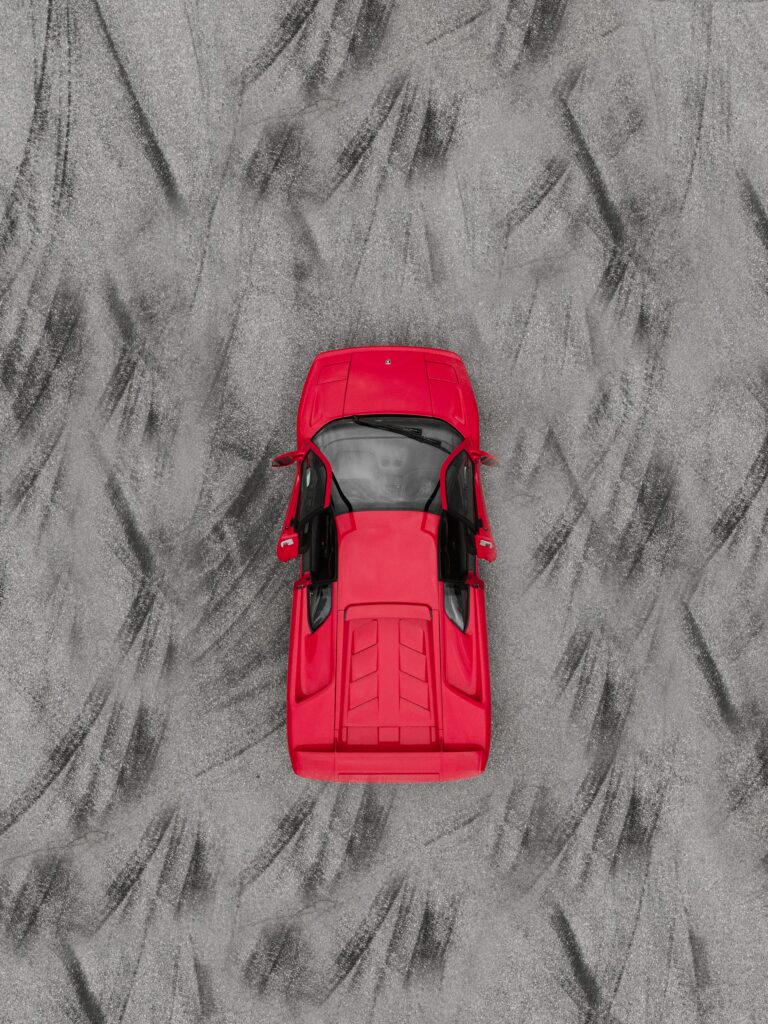Aerial View of Striking Red Sports Car on Textured Background Wallpaper