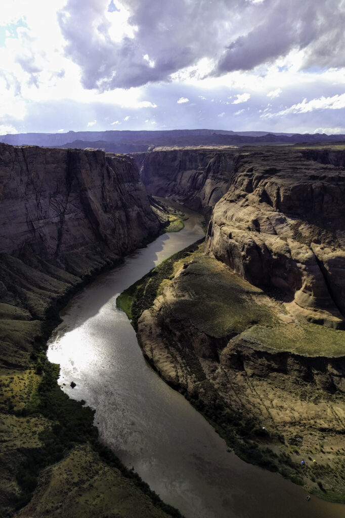 Aerial view of winding river through rugged canyon with steep cliffs and dramatic sunlight Wallpaper
