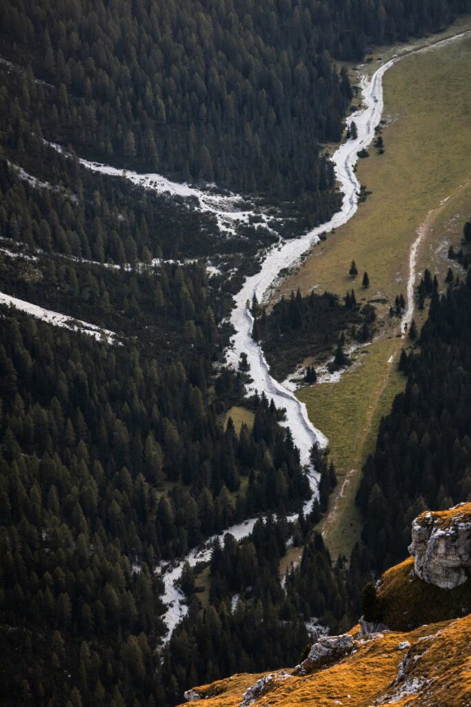 Aerial view of winding river through lush green forest and rocky slopes valley landscape wallpaper
