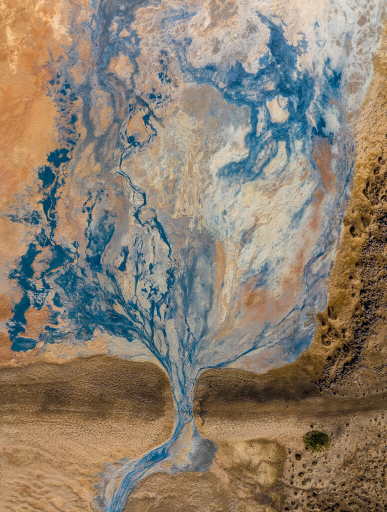 Aerial view of winding blue river and earthy banks with natural textures and patterns wallpaper