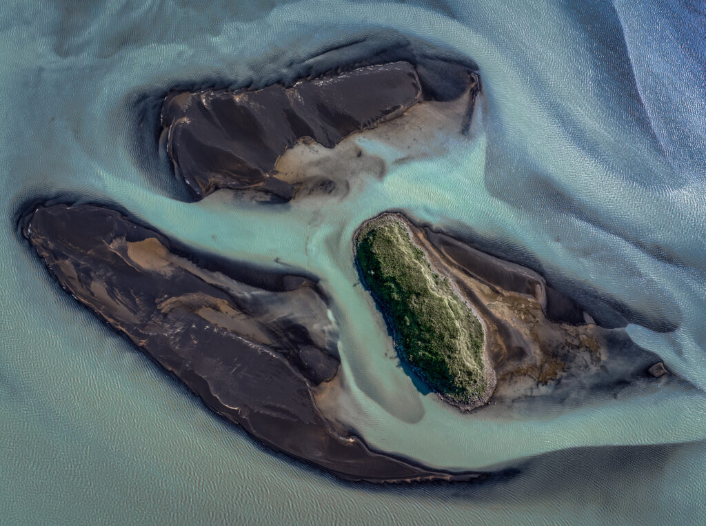 Aerial view of winding river braids with sand bars vibrant greens blues natural landscape pattern Wallpaper