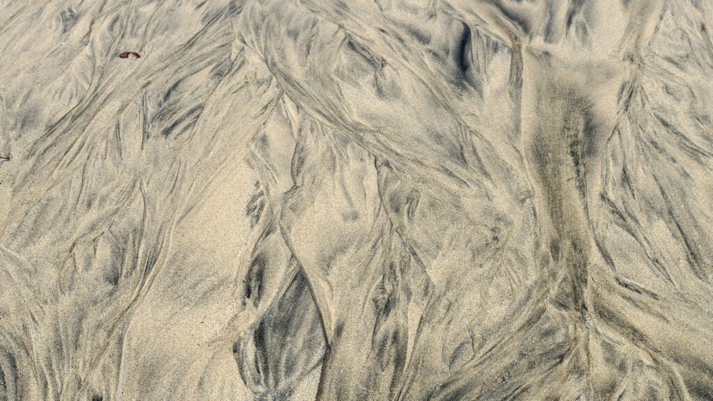 Aerial view of desert sand dunes with intricate patterns and soft earthy tones wallpaper background