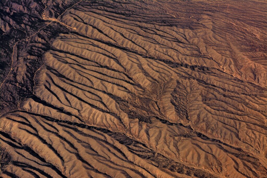 Aerial view of desert landscape with winding ridges erosion patterns and warm sunlight textures Wallpaper