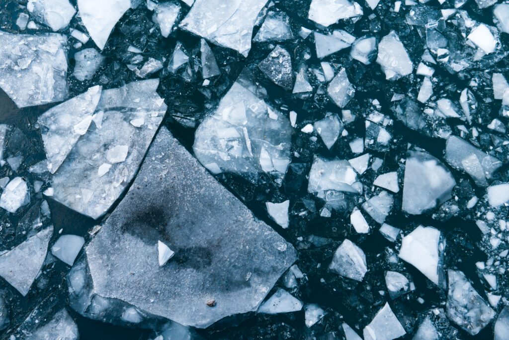 Aerial view of fragmented ice floes on deep blue water with sharp geometric shapes wallpaper