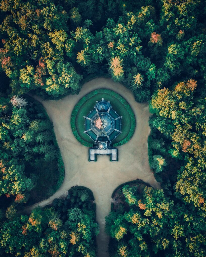 Aerial view of historic building surrounded by dense green trees and winding forest trails wallpaper