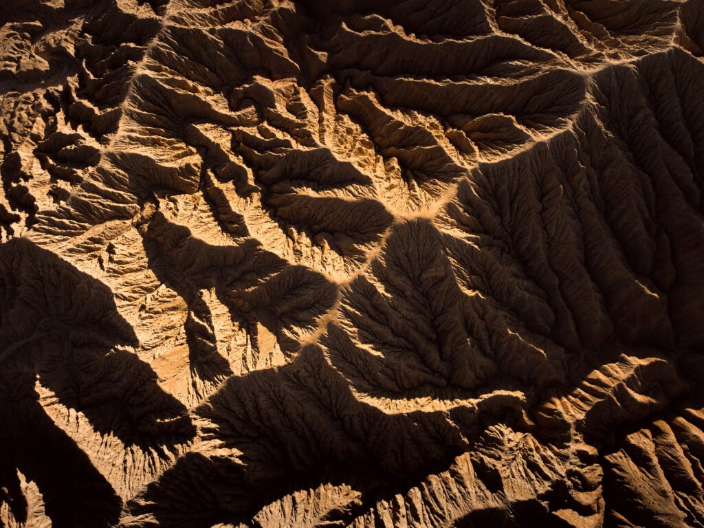 Aerial view of rugged brown mountains with detailed ridges and valleys natural textured landscape Wallpaper