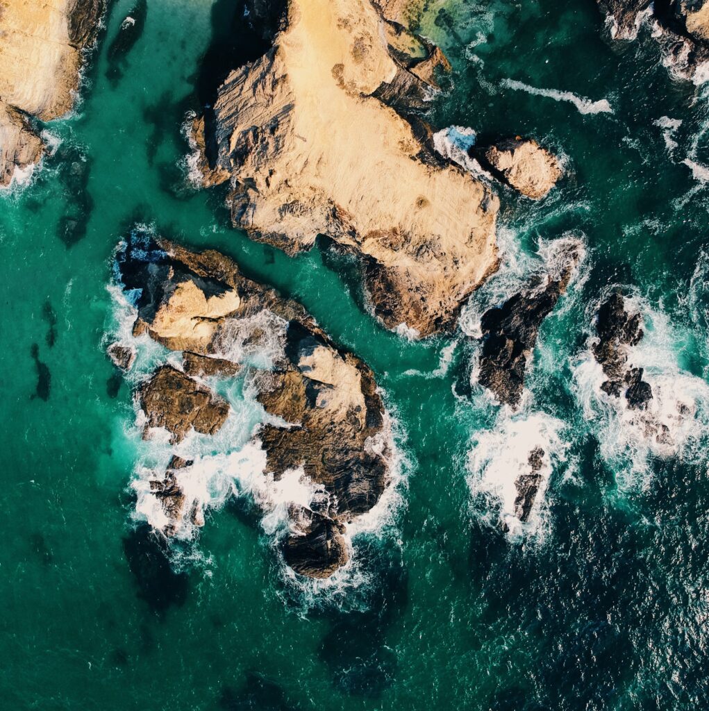 Aerial view of island with rugged rocky shores and turquoise ocean waters coastal wallpaper background