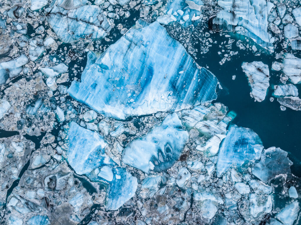 Aerial view of sea with large and small ice fragments in blue and white tones wallpaper background