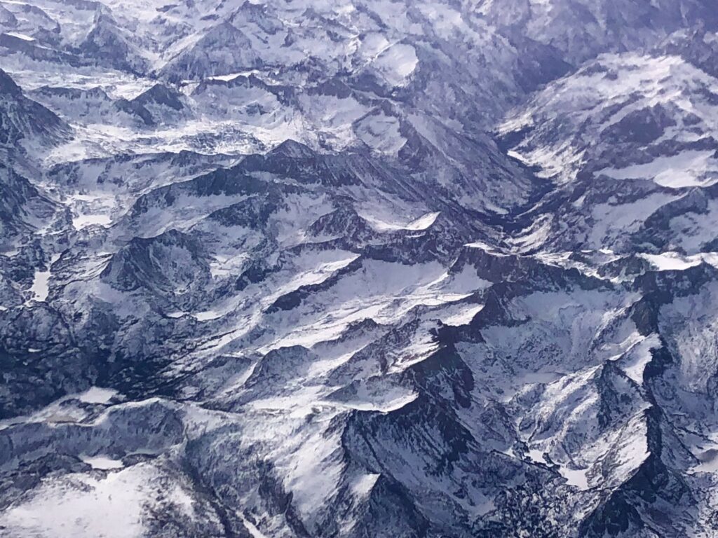 Aerial view of rugged snow-dusted mountains with blue and grey textured terrain wallpaper background