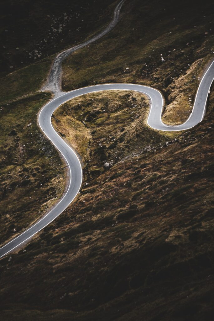 Aerial view of winding road with sharp curves through rugged sloping terrain landscape wallpaper