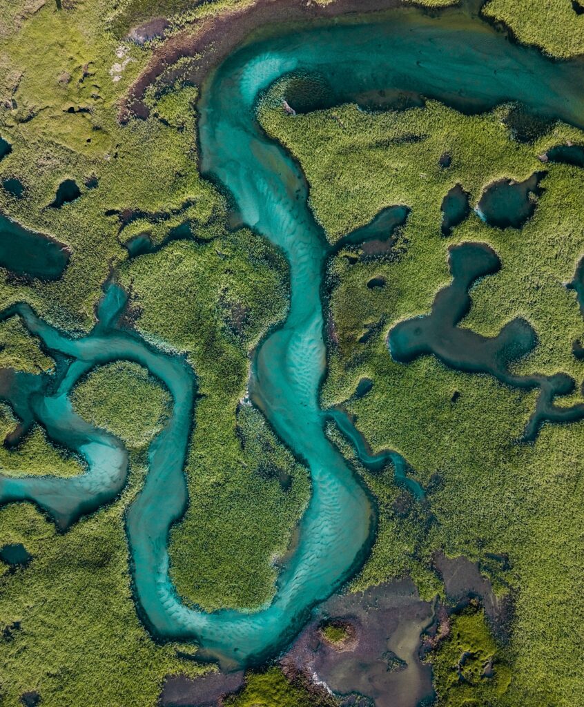 Aerial view of winding turquoise river flowing through lush green landscape nature wallpaper background