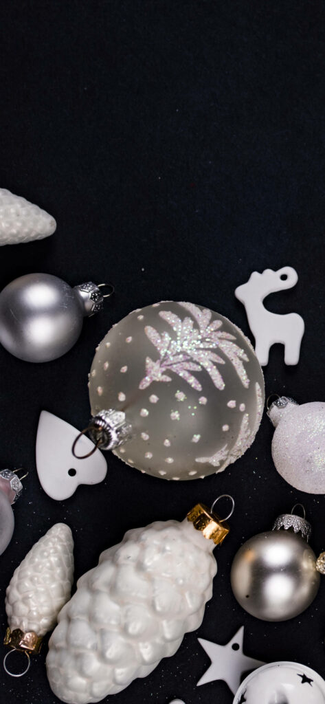 Dainty Elegance: A Sleek Christmas iPhone Wallpaper Embellished with a Silver Bauble and Charming Decorations on a Chic Black Background