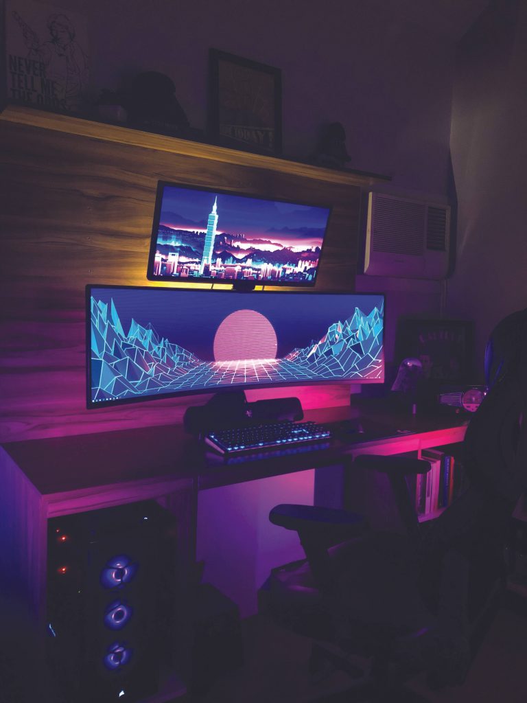 Aesthetic gaming room with stacked ultrawide monitors showing synthwave and Taipei 101 skyline Wallpaper