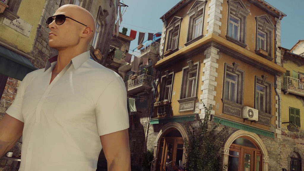 Agent 47 in white shirt and sunglasses on sunlit Italian street via Paradiso Hitman wallpaper background