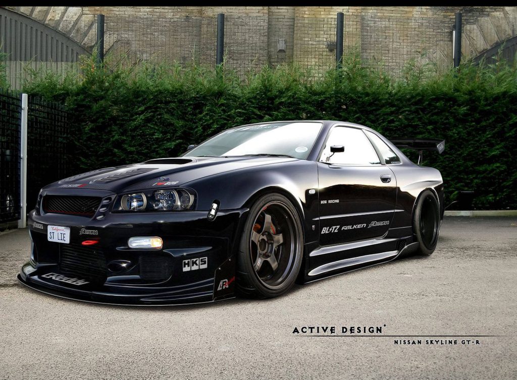 Black Nissan Skyline GT-R R34 with lowered stance deep-dish wheels and HKS Blitz decals Wallpaper