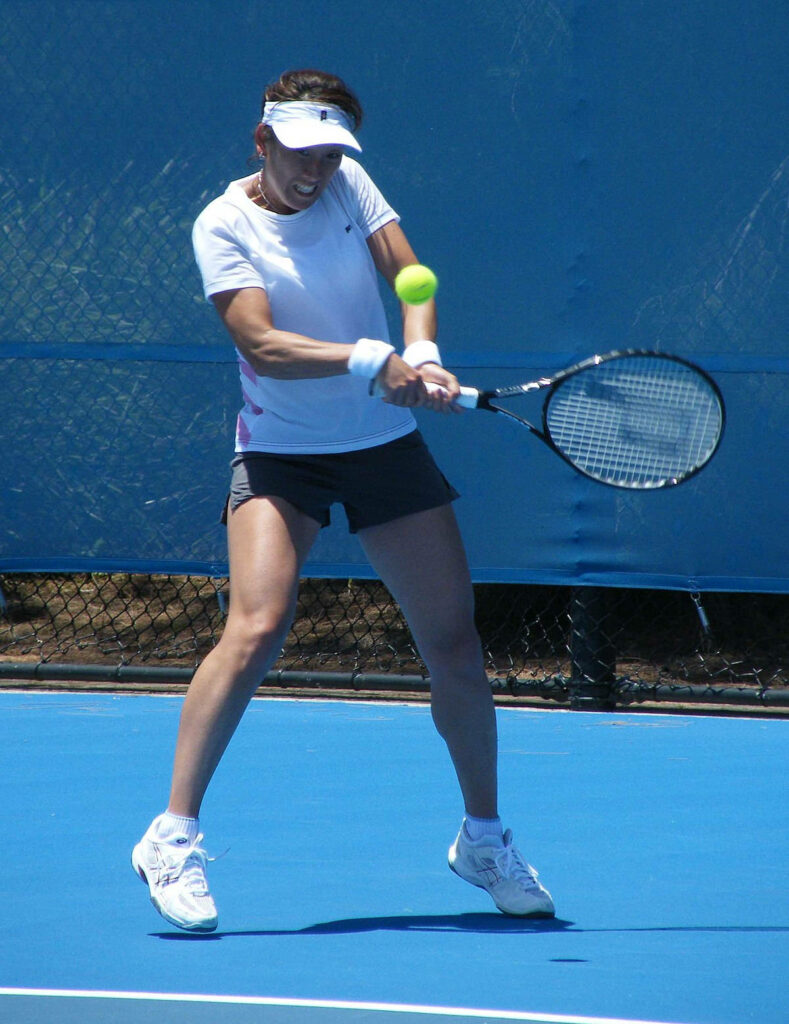 Ai Sugiyama hitting powerful two-handed backhand with intense focus on blue hard tennis court Wallpaper