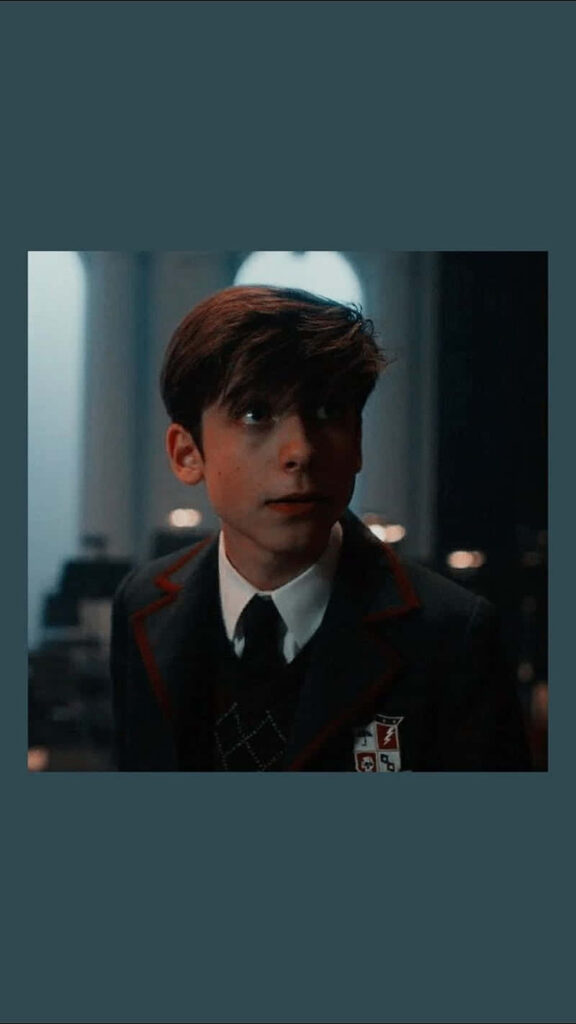Aidan Gallagher in formal school uniform with crest against soft blurred background wallpaper