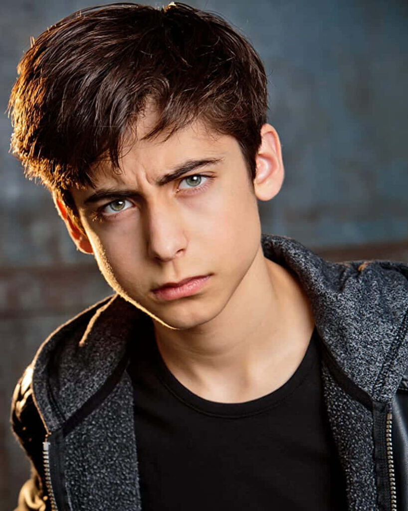 Aidan Gallagher in black jacket and pants with intense serious look wallpaper background